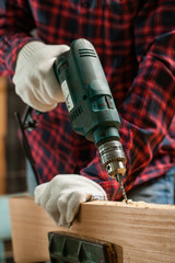 Man drills the wooden plank