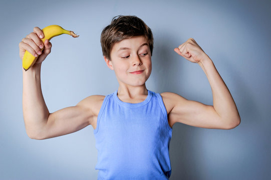Junge mit Banane zeigt seine Muskeln