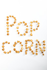 top view of popcorn lettering made of popcorn kernels on white