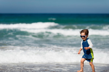 Little boy running away from waves