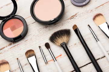close up view of various brushes and cosmetics for applying makeup on table
