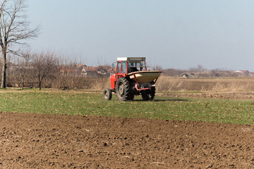 Fototapeta premium Tractor spreading artificial fertilizers