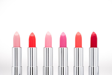Close-up view of fashionable glossy lipsticks set on white background