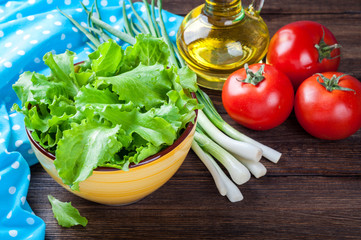 Cooking salad. Healthy food concept background with copy space. Organic vegetables - lettuce, green onions, tomatoes and olive oil, salt on wooden table. Top view