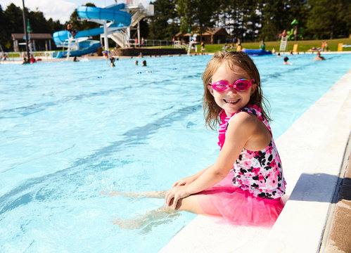 Portrait of happy little girl sitting on pool edge