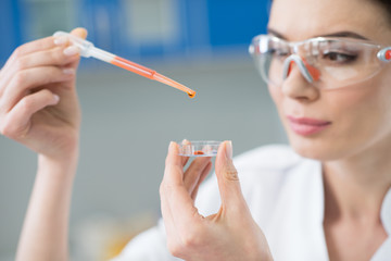 close up of woman scientist in protective glasses working in lab