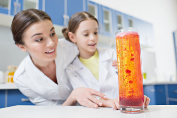low angle view of excited woman teacher and girl student scientists looking at experimental tube in lab