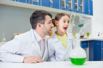 Obraz premium portrait of smiling man teacher looking at excited girl student during experiment in lab