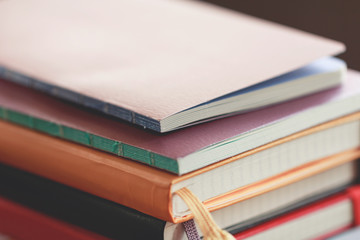 A stack of colored books and notepads on the table. Yellow and violet tones. Educational concept.