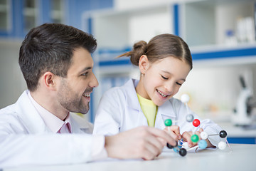 Smiling teacher and student scientists looking at molecule model in lab