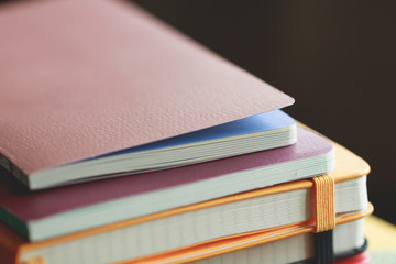 A stack of colored books and notepads on the table. Yellow and violet tones. Educational concept.