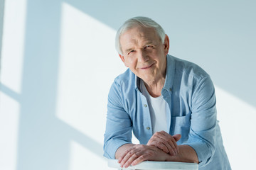 portrait of smiling senior man in casual shirt on white