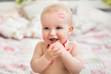 Image of adorable child with red kisses on the skin, happy boy, sitting in the Studio on the bed, angel, romantic holiday, Valentine's Day.