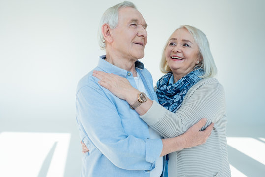 Portrait Of Happy Senior Couple Hugging On White