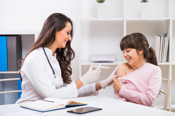 Female doctor giving injection to a child at medical office.