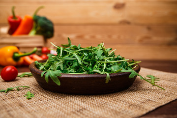 Arugula leaves in bowl. Fresh salad. Natural raw vegetables. Organic bio food on rustic wooden table.