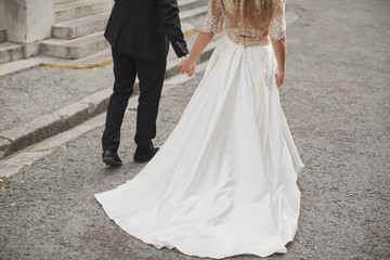 Obraz na płótnie Canvas Bride and groom walking together holding their hands
