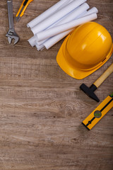 Adjustable wrench, hammer and building level. Architecture plans and helmet. Wood rustic background.