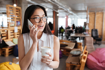 Happy woman drinking coffee lattee and talking on mobile phone