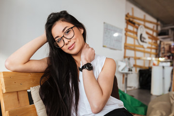 Smiling young woman in glasses sitting indoors