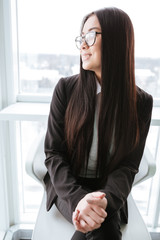 Happy businesswoman in glasses sitting and looking at the window