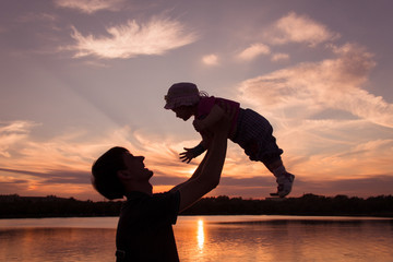 Father and little daughter silhouettes at sunset