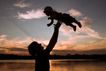 Father and little daughter silhouettes at sunset
