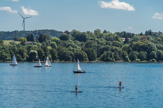 Starnberger See mit Stehpaddlern und Segelbooten und einem Windrad