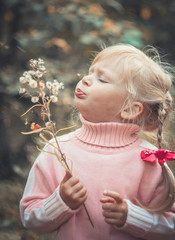Little blonde girl blowing dandelion
