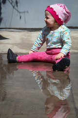 little funny girl playing with water in puddle