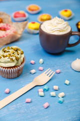 Macaroons, cupcakes and donuts. Mug with whipped cream. Almond macaron cookies with marshmallows. Sweet dessert.