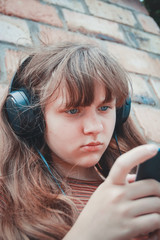 teenage concept - teenage girl with headphones listening to music outside
