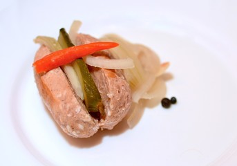 Portion of one traditional czech pickled sausage in sour brine with cucumber, onions and red hot peppers.