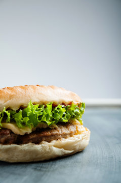 Delicious juicy burger with grilled meat, salad and chees on gray teable, vertical image