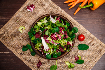 Provence mix salad. Leaves of endive or chicory, lamb and rose salad. Raw vegetables. On wooden table.