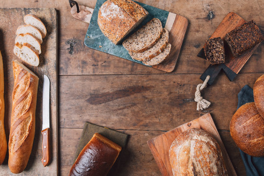 From Above Photo Of Bread On Cutting Board On Wooden Table At Bakery.