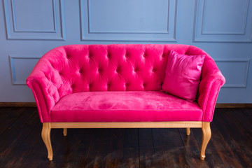 Pink sofa on a blue wall background. Indoors