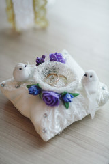 Wedding rings in white textile box with birds and flowers on wooden table