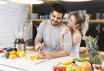 Young couple cutting fruit in the kitchen 