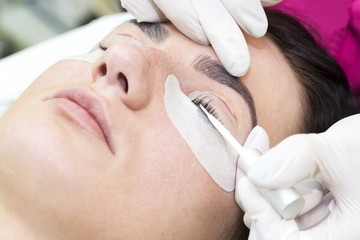 Obraz na płótnie Canvas Woman on the procedure for eyelash extensions, eyelashes lamination 