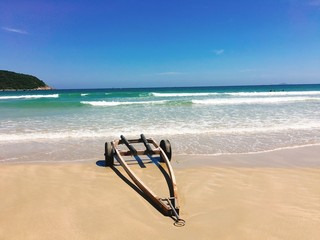 Fototapeta na wymiar The wheelbarrow on the beach with sea wave foam