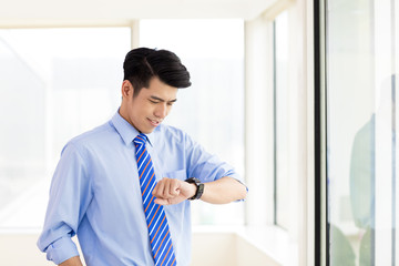 Businessman checking time from watch in office