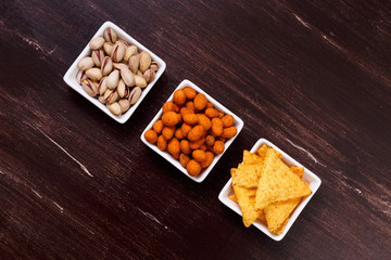 Nachos chips. Tortilla snacks. Mexican salsa and pistachios nuts. On rustic wooden background.