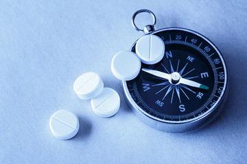 White aspirin pills and compass © Sergey Yarochkin