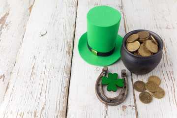Happy St Patricks Day leprechaun hat with gold coins and lucky charms on vintage style white wood background. Top view