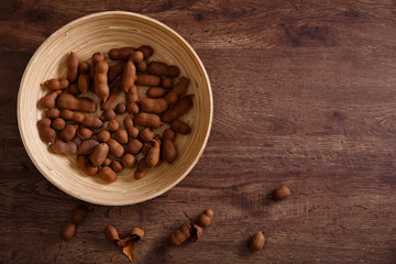 Sweet tamarind on grunge rustic wood background. Natural organic diet food with a lot of vitamins. Plate dish or bowl on wooden board.