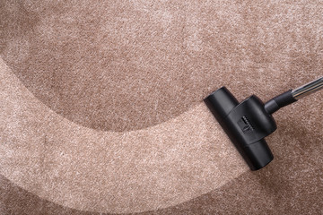 Vacuuming carpet with vacuum cleaner. Housework service. Close up of the head of a sweeper cleaning device.
