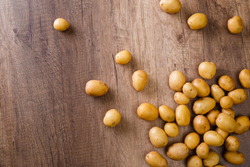 Potatoes on wooden table. Raw new potato. Fresh natural vegetables. Organic bio food on rusticn background.