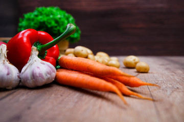 Vegetables. Potatoes, carrot and red pepper. Lettuce salad and garlic. Natural organic bio food. Wooden basket on rustic table.