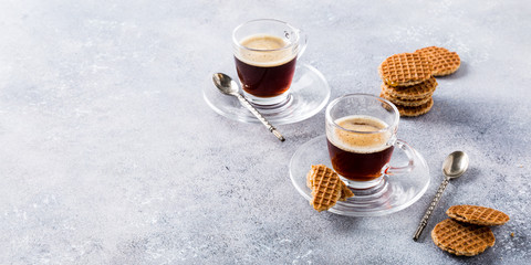 Glass cups of coffee with mini stroopwafel, syrupwaffles cookies on light gray background with copy...